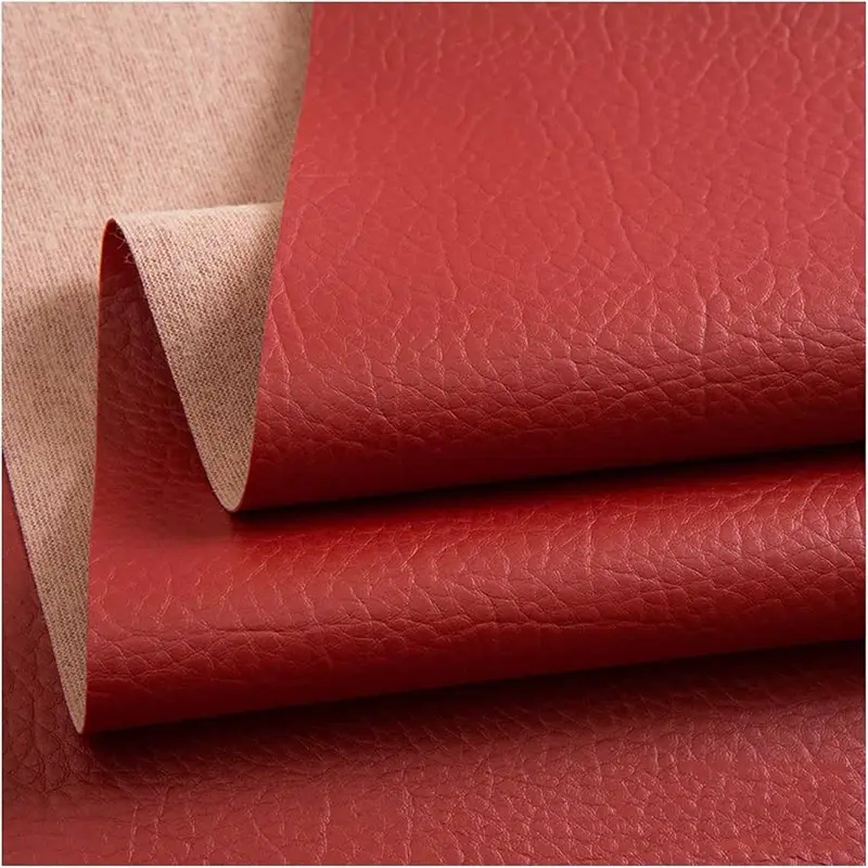 Rollo de cuerina roja para tapizar, doblado para mostrar el grano tipo cuero de la cara vista y la base textil del revés